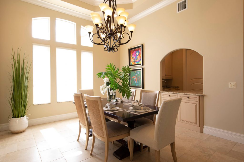 Dining room with a chandelier and tall windows blown out to white, before editing