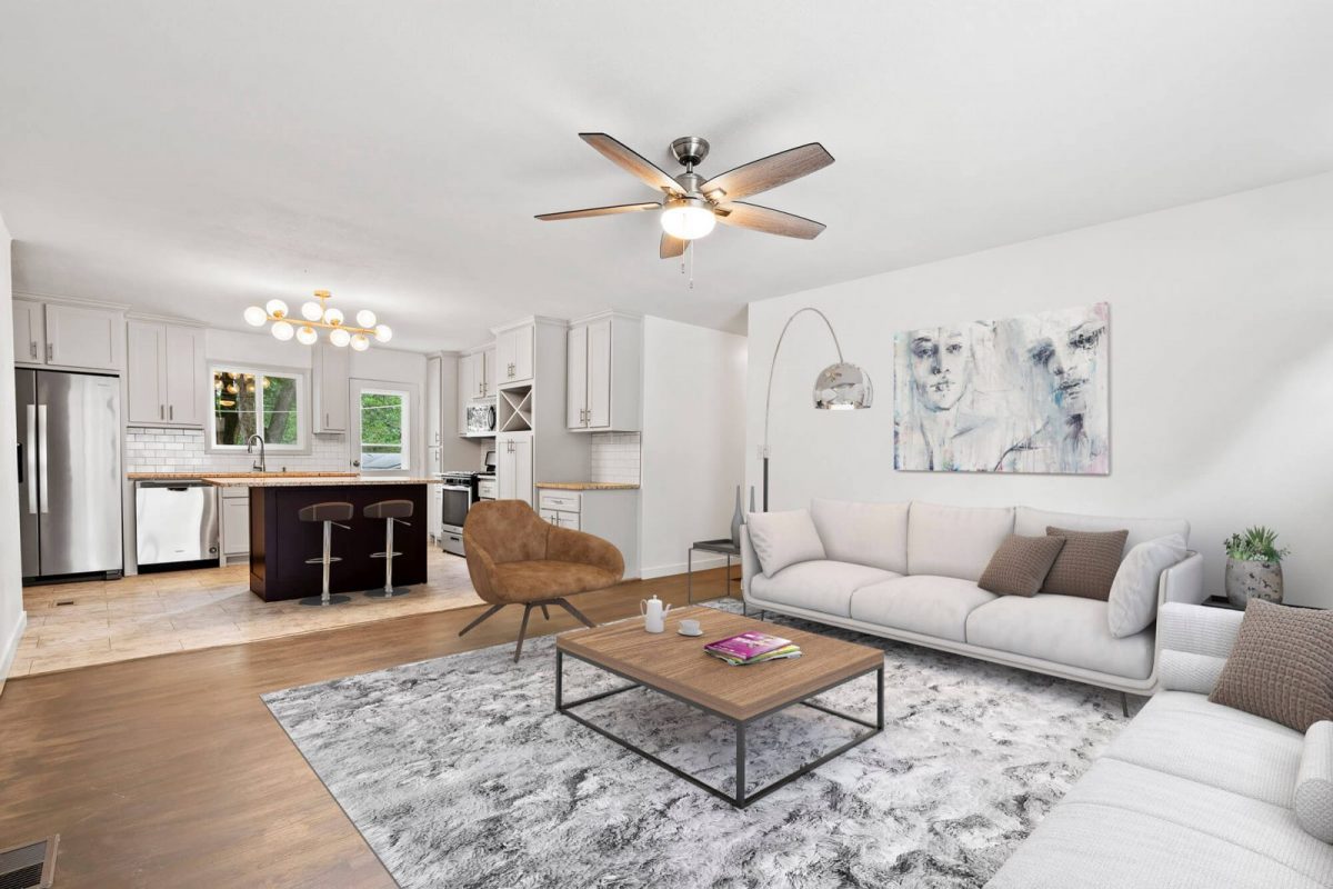 Open-plan room virtually staged with sofas, a rug, lamps and artwork