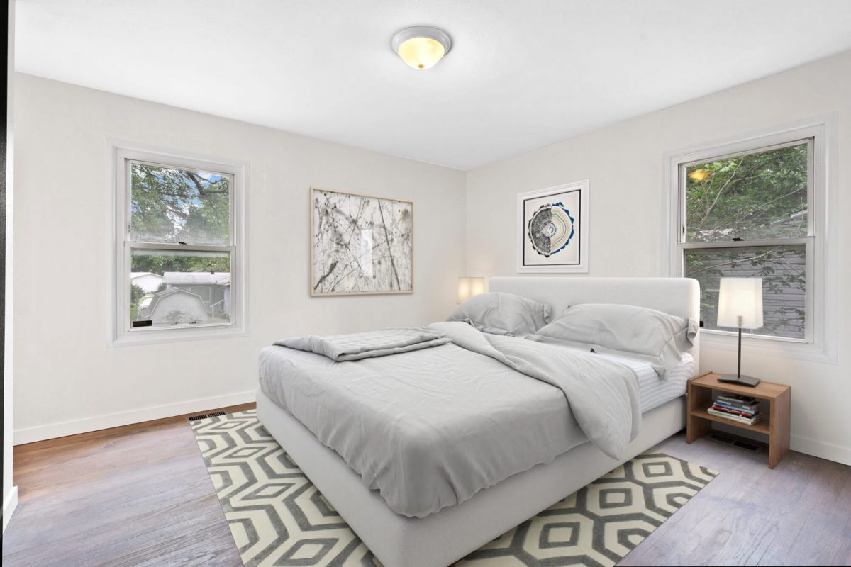 The same room after virtual staging, furnished as a bedroom with a bed, rug, side table and artwork