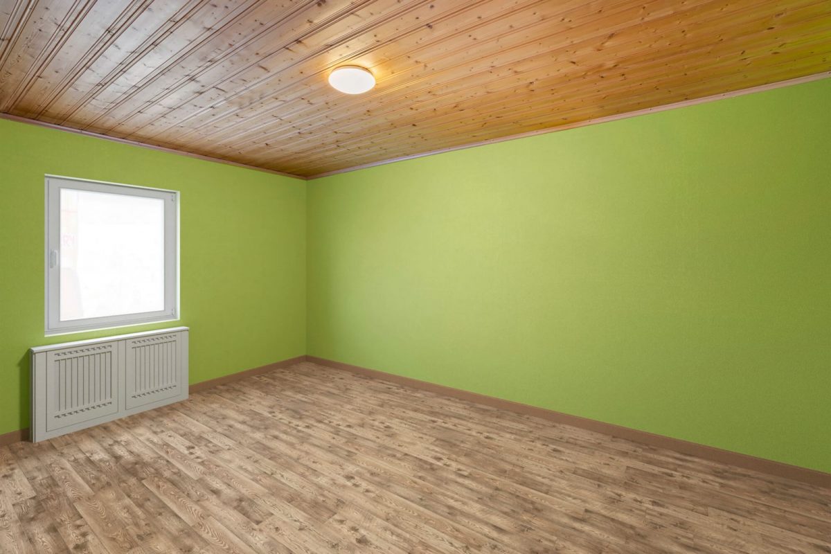 The same room after item removal, empty with green walls and a wood floor