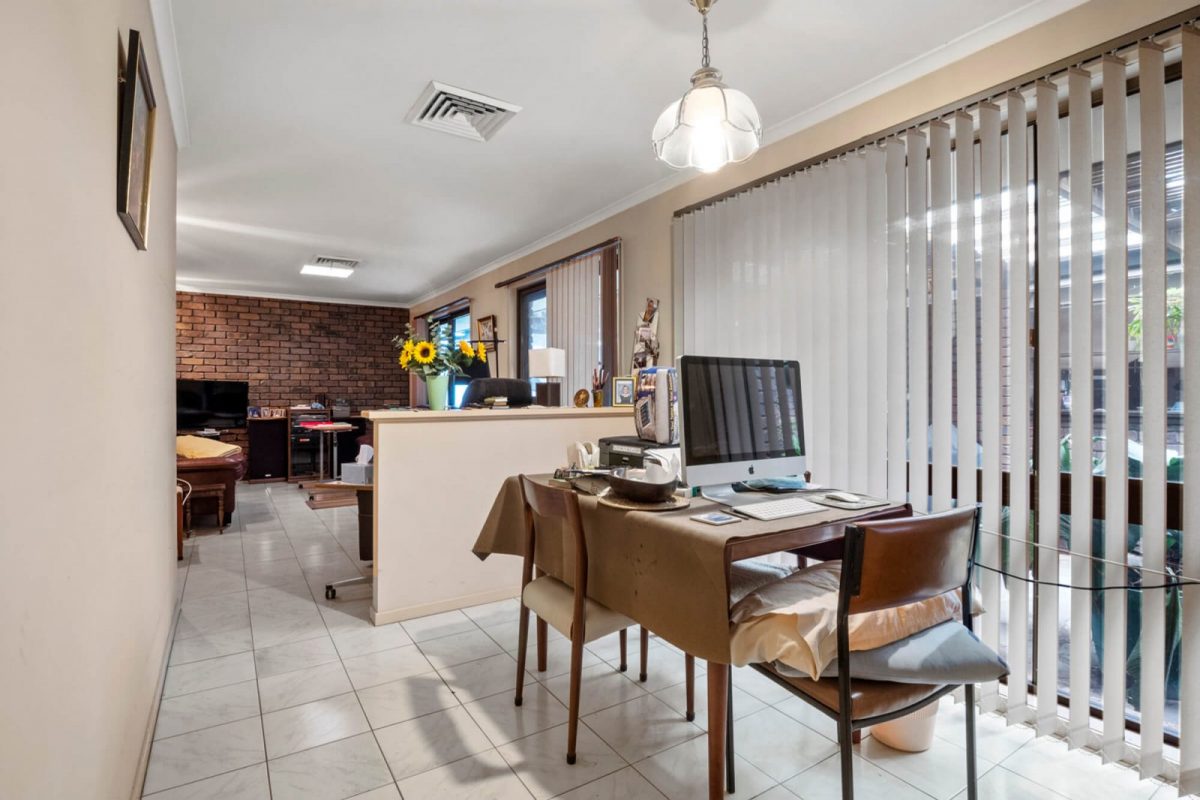 Open-plan room with a desk, computer, chairs and personal items, before item removal