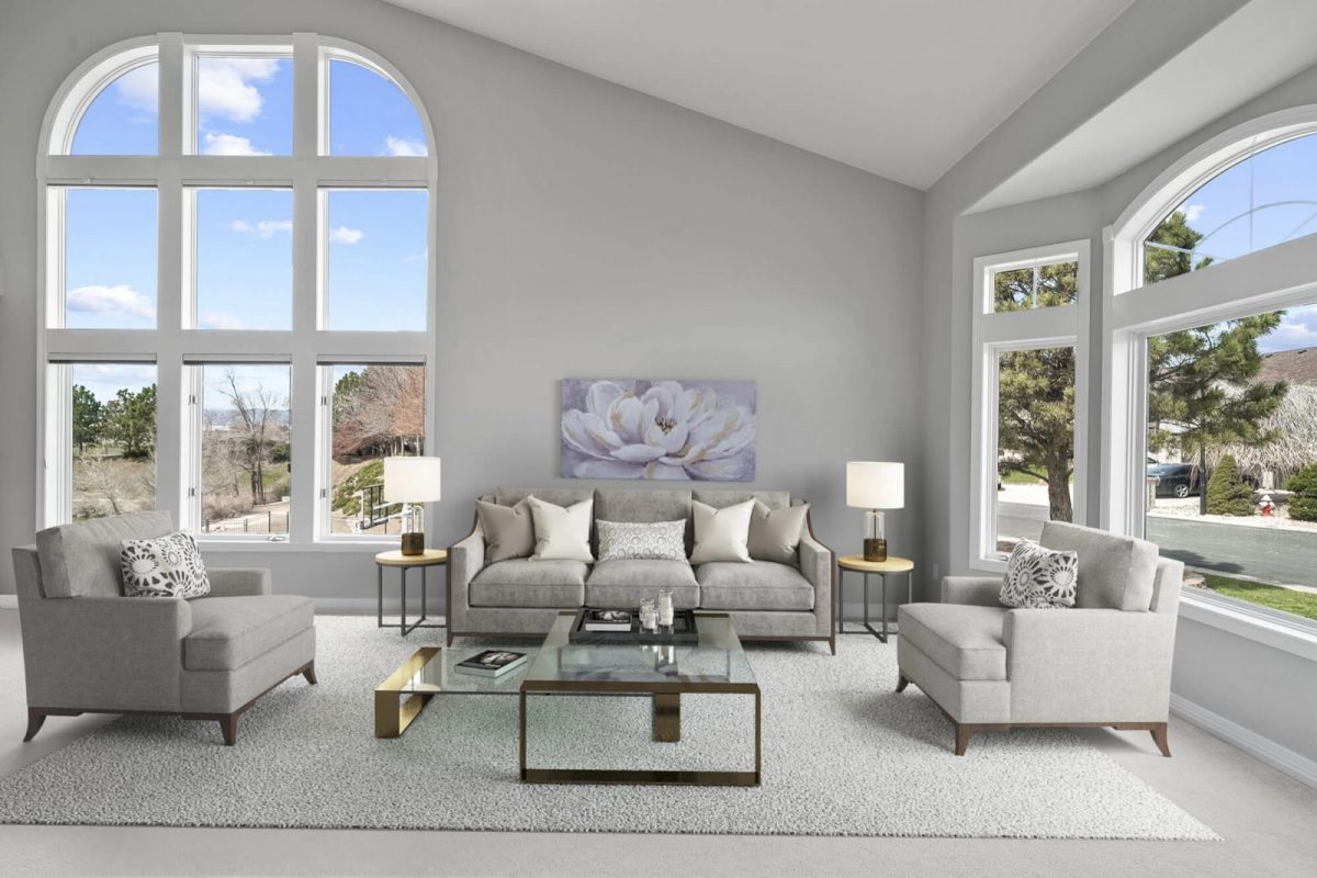 Living room with tall arched windows, virtually staged with sofas, a rug and a coffee table